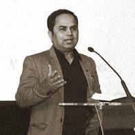 Portrait of Raj Deokar, OMPEG Core Group, speaking at a lectern.
